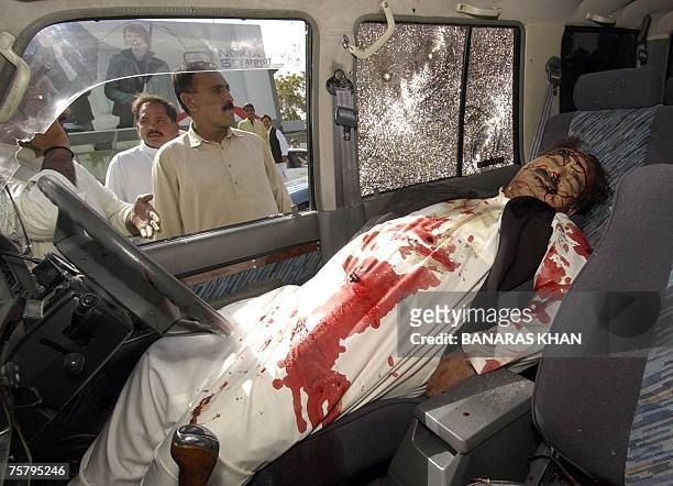 Pakistani bystanders look at the body of Baluchistan provincial spokesman, Raziq Bugti as it lies in a vehicle after gunmen shot him dead in Quetta,...
