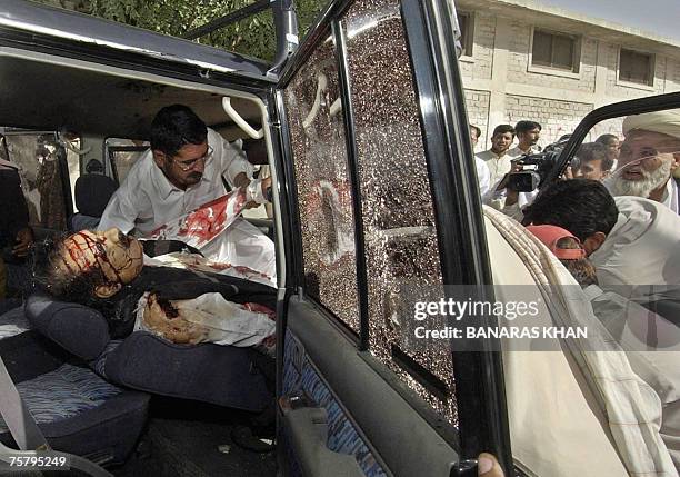 Pakistani officials remove the body of Baluchistan provincial spokesman, Raziq Bugti from his vehicle after gunmen shot him dead in Quetta, 27 July...