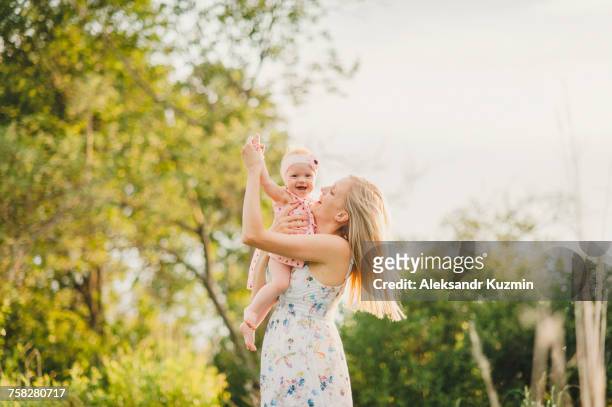 mother playing with baby daughter on sunny day - baby dancing stock-fotos und bilder