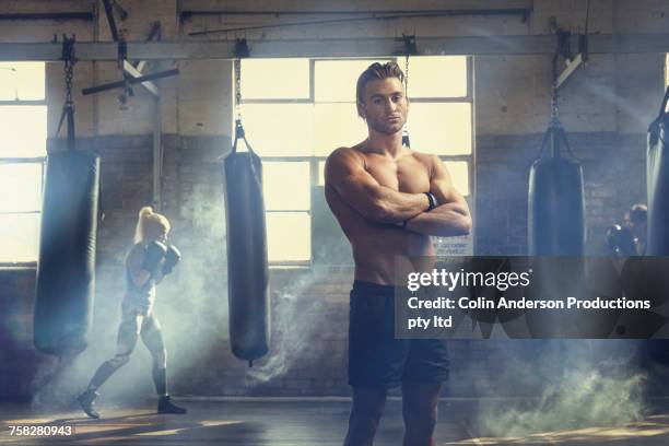 confident man posing near punching bags in gymnasium - boxing shorts stock-fotos und bilder