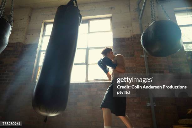 hispanic man hitting punching bag in gymnasium - punching bag stock pictures, royalty-free photos & images