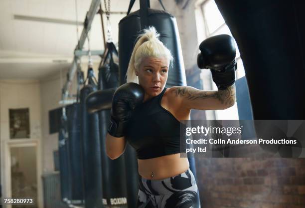 caucasian woman hitting punching bag in gymnasium - boxboll bildbanksfoton och bilder