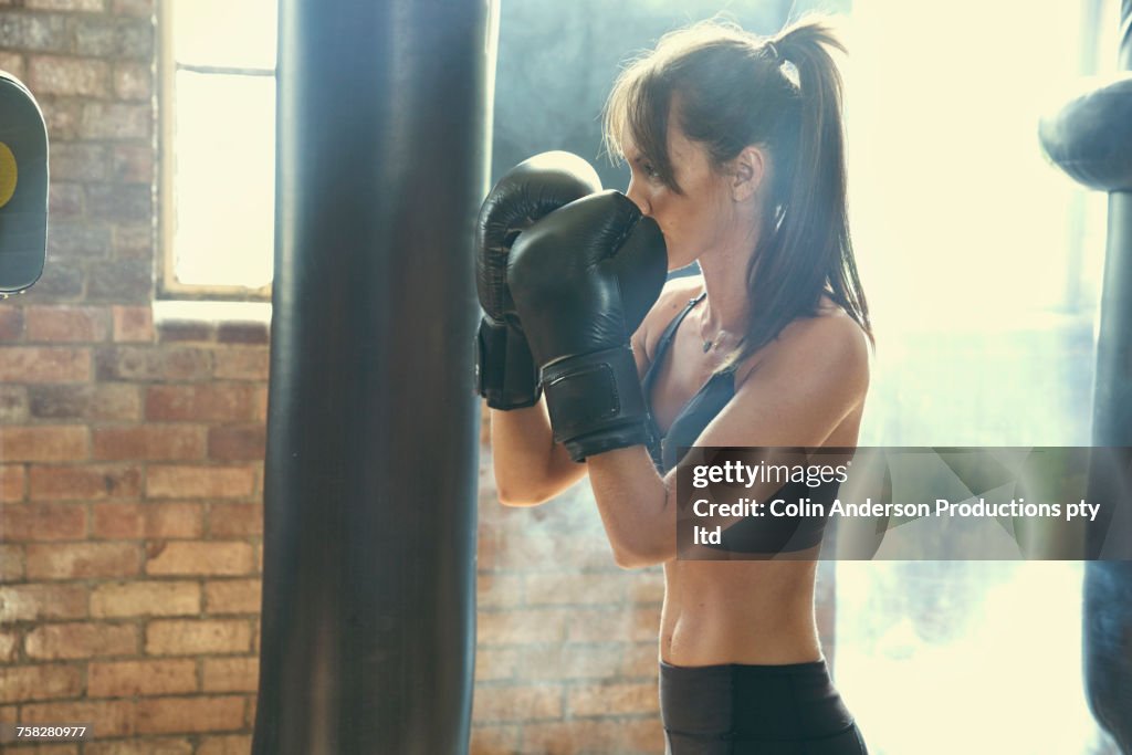 Pacific Islander woman hitting punching bag in gymnasium