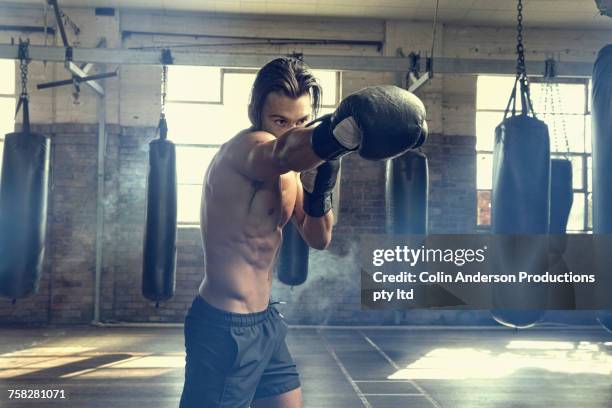 hispanic boxer punching in gymnasium - boxing shorts stock-fotos und bilder