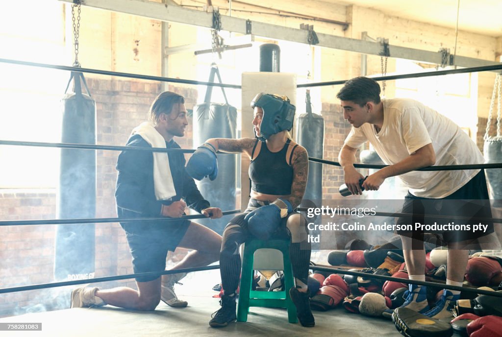 Trainers talking to boxer on stool in boxing ring