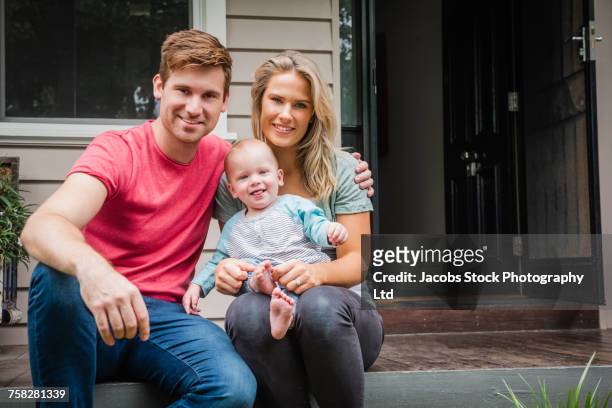 portrait of caucasian couple with baby son sitting on porch - melbourne homes stockfoto's en -beelden