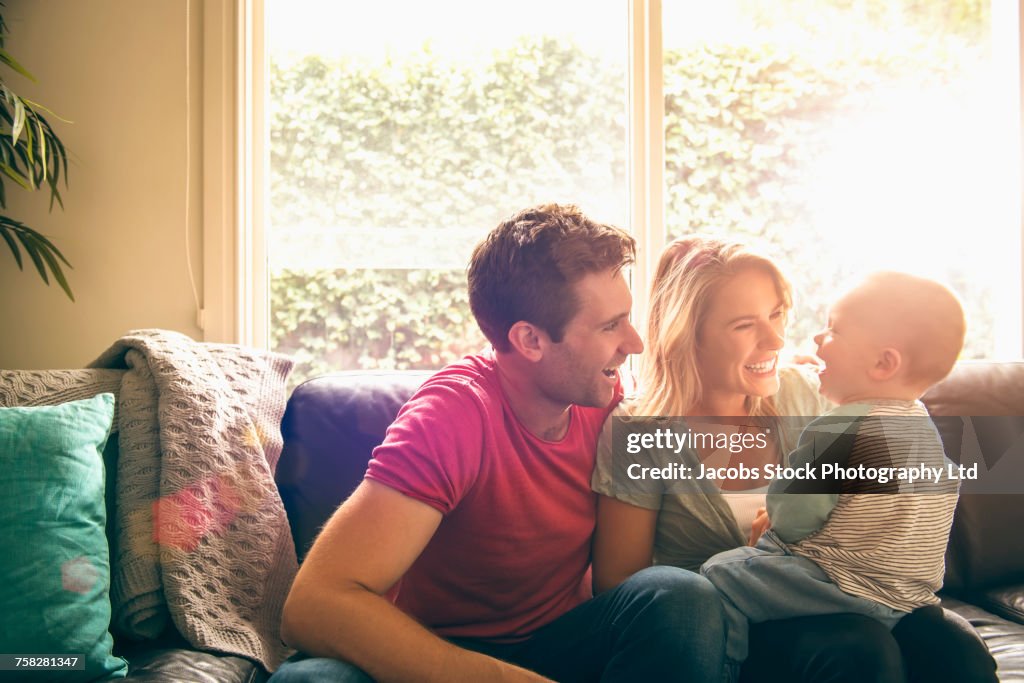 Caucasian couple playing with baby son on sofa