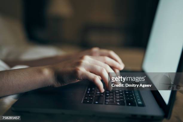 hands of caucasian woman typing on laptop in bed - journalist stock-fotos und bilder
