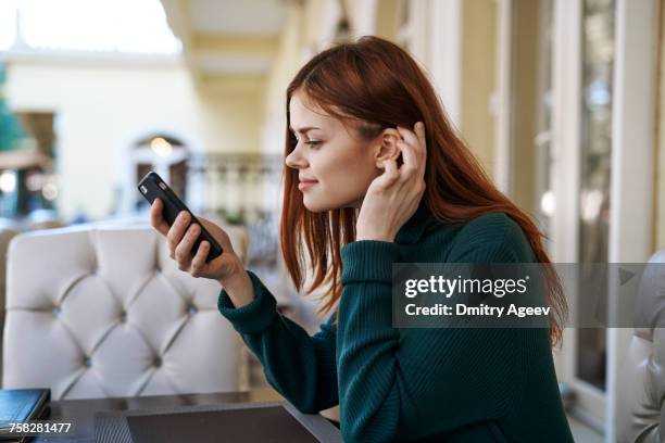 caucasian woman texting on cell phone at restaurant - mesa cafeteria perfil fotografías e imágenes de stock