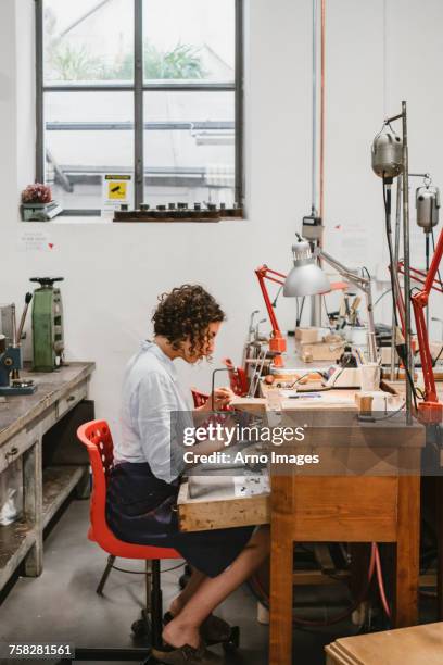 female jeweller using coping saw at workbench - laubsäge stock-fotos und bilder