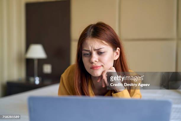 confused caucasian woman laying on bed using laptop - confused 個照片及圖片檔