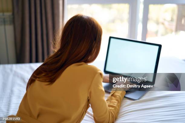 caucasian woman laying on bed using laptop - lying on back ストックフォトと画像