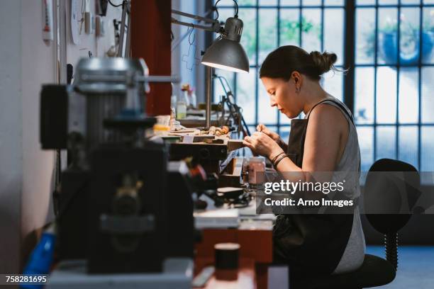 female jeweller at work in jewellery workshop - schmuck stock-fotos und bilder