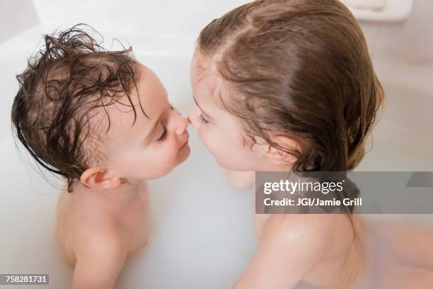 caucasian boy and girl rubbing noses in bathtub - milchbad stock-fotos und bilder