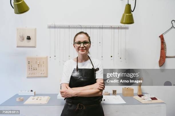 portrait of female jeweller with arms folded in jewellery workshop - juwelier stock-fotos und bilder