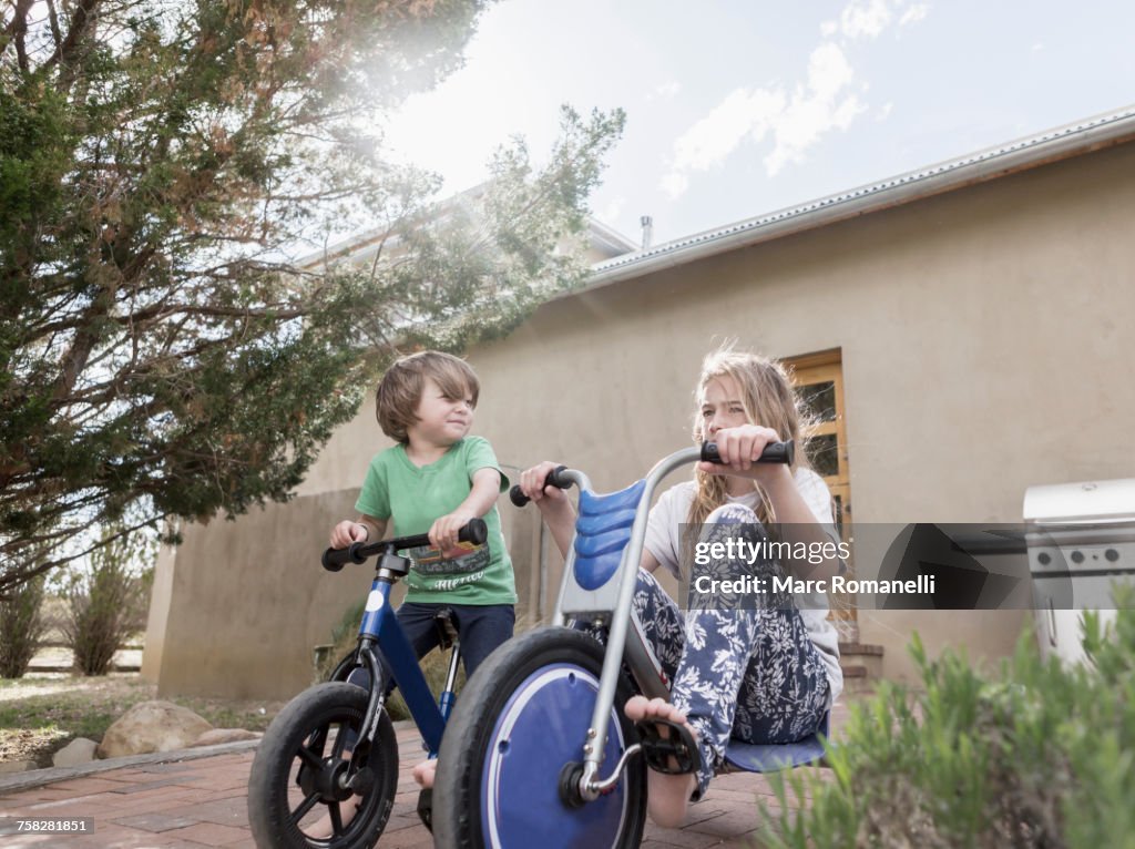 Caucasian boy and girl riding bicycles near house