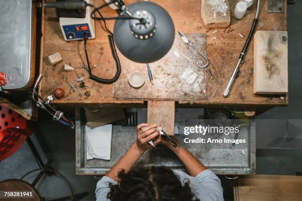 overhead view of female jeweller using coping saw at workbench - laubsäge stock-fotos und bilder