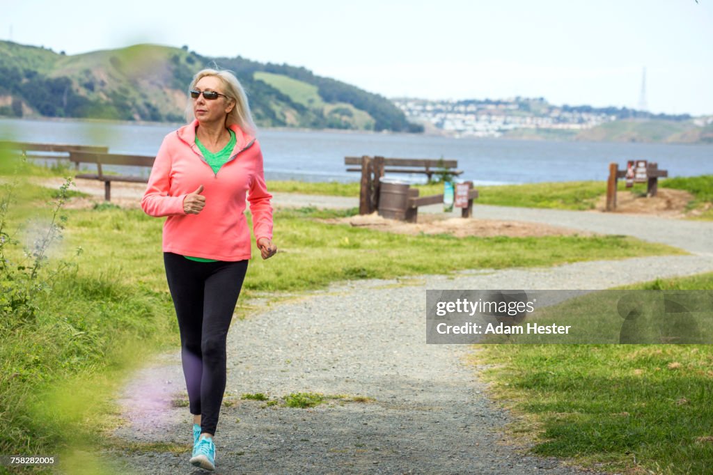 Older Caucasian woman running on path in park