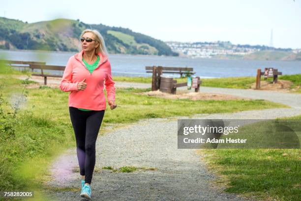 older caucasian woman running on path in park - one senior woman only stock pictures, royalty-free photos & images
