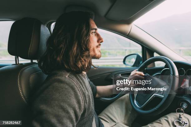 young man driving car on rural road - car interior side stock pictures, royalty-free photos & images