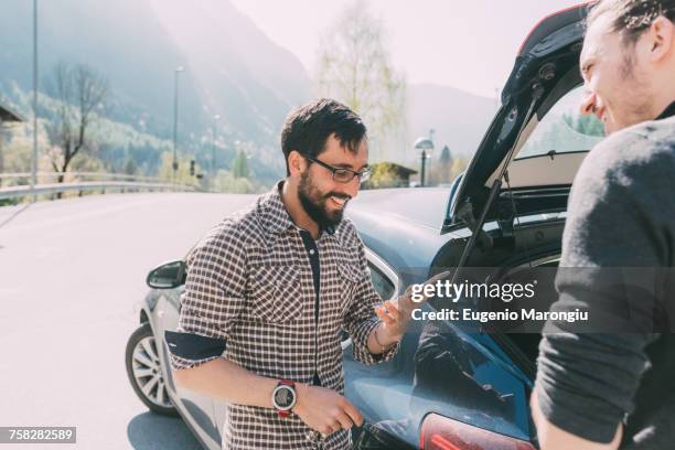 two men looking at smartphone by car on rural road, lombardy, italy - cell mates stock-fotos und bilder