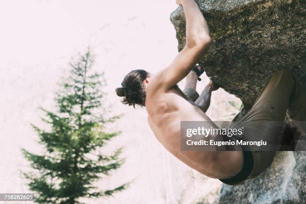 bare chested male boulderer climbing boulder, lombardy, italy - 胴上げ ストックフォトと画像