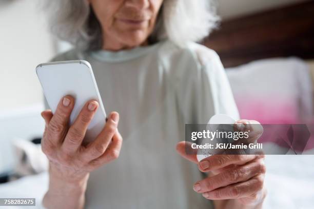 older woman checking prescription with cell phone - drug bust stock pictures, royalty-free photos & images