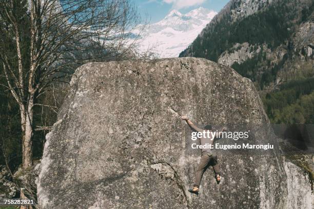 rear view of young male boulderer climbing boulder, lombardy, italy - 胴上げ ストックフォトと画像