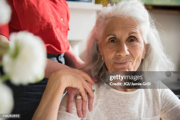 hand of daughter on shoulder of older mother - mother daughter holding hands stock pictures, royalty-free photos & images