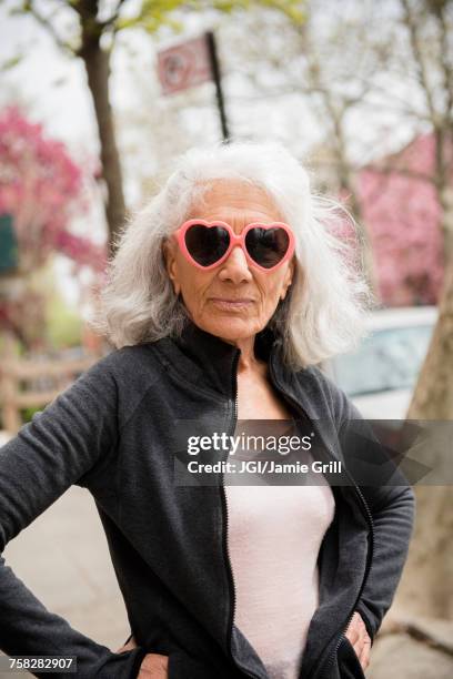 older woman wearing heart-shape sunglasses - rebellion photos et images de collection