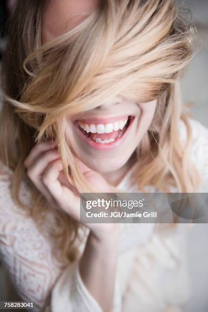 laughing caucasian woman covering eyes with hair - haarpflege stock-fotos und bilder