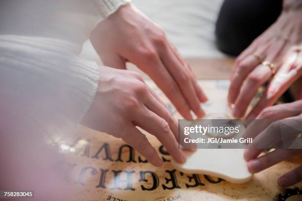 hands of caucasian women using a ouija board - paranormaal stockfoto's en -beelden