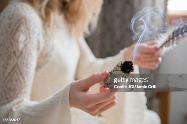 caucasian woman holding a feather and ritual incense - feierliche veranstaltung stock-fotos und bilder