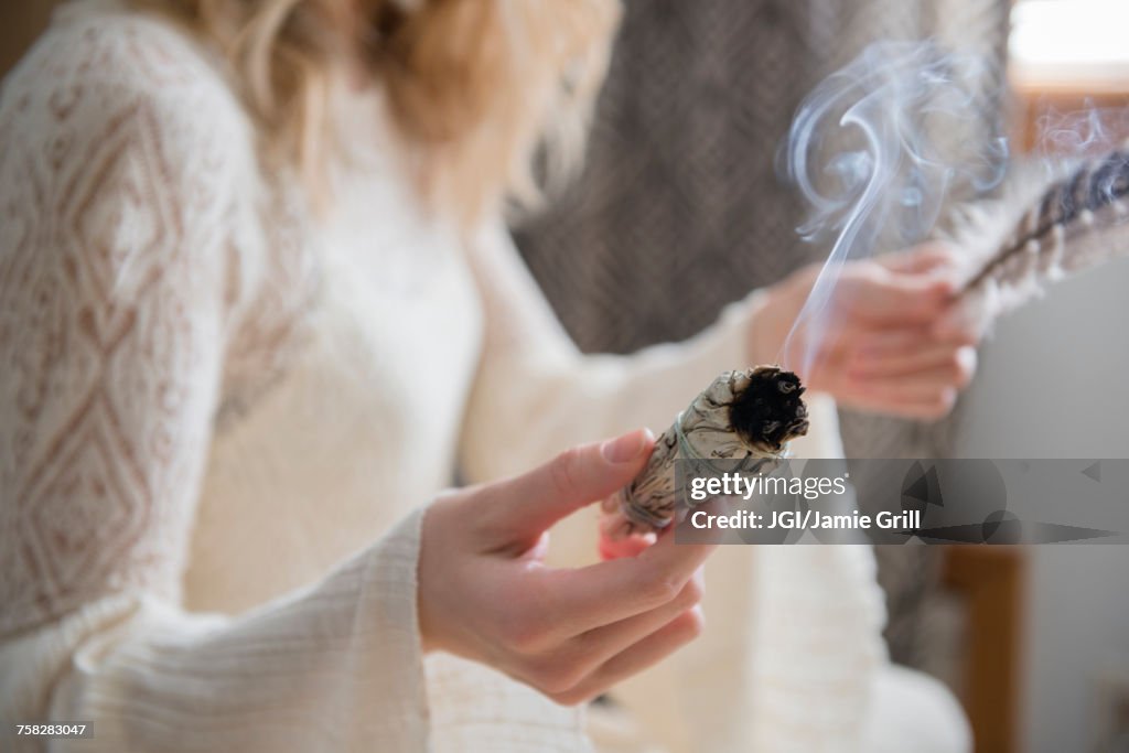 Caucasian woman holding a feather and ritual incense