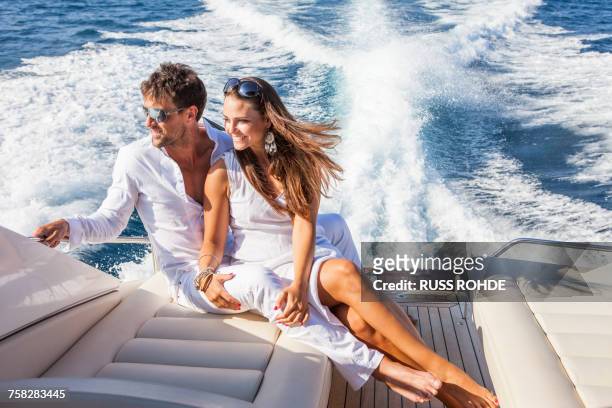 couple relaxing on yacht, on water, looking at view - millionnaire stock-fotos und bilder
