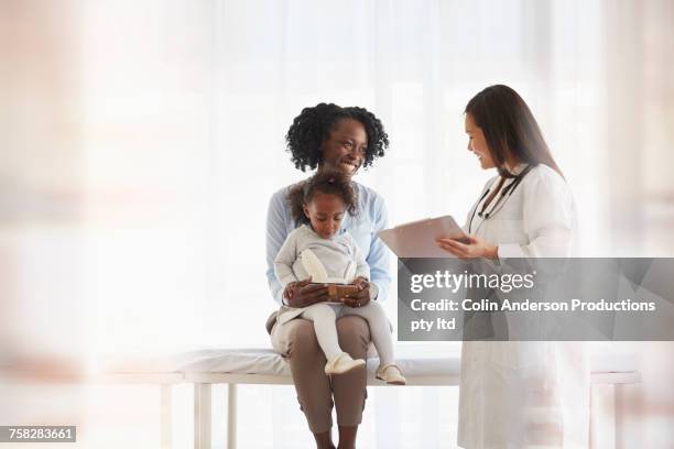 doctor talking to mother holding daughter in last - doctor stethoscope patient whole body stock pictures, royalty-free photos & images