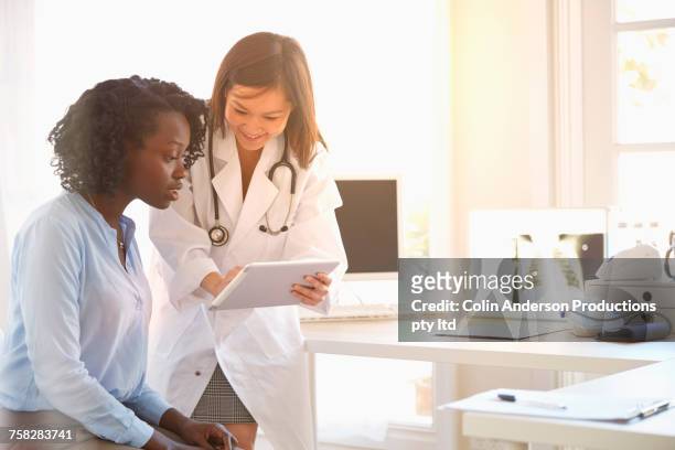doctor and woman reading digital tablet - display cabinet photos et images de collection