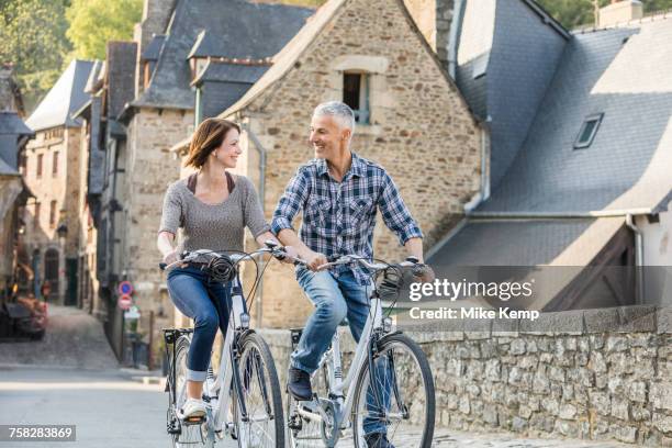 caucasian couple riding bicycles in city - france dinan stock pictures, royalty-free photos & images