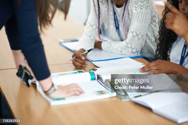 teacher in classroom helping students study - text book stock pictures, royalty-free photos & images