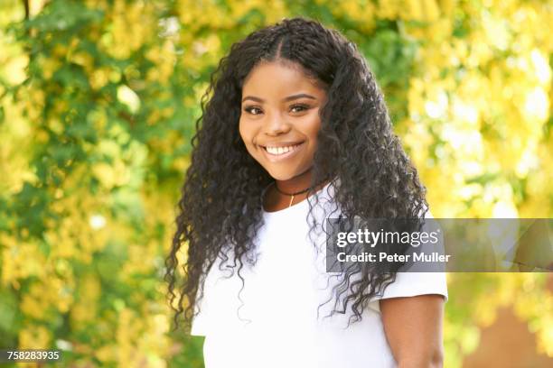 portrait of curly haired teenage girl looking at camera smiling - curly girl stock pictures, royalty-free photos & images