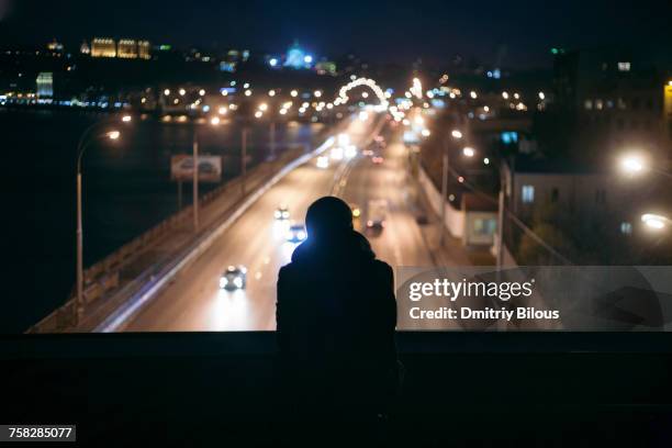 silhouette of person watching traffic from overpass at night - ergens overheen kijken stockfoto's en -beelden