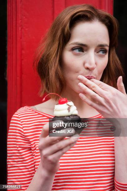 caucasian woman holding a cupcake licking finger - women licking women stock-fotos und bilder