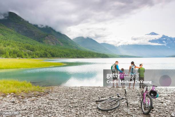 couple with son and daughter riding bicycles near lake - two kids with cycle stock-fotos und bilder