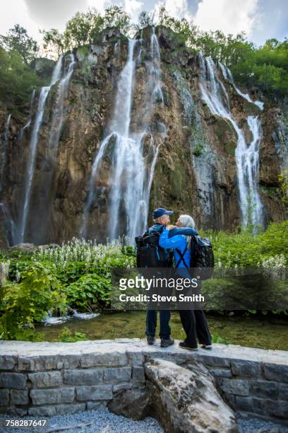 older caucasian couple hugging near waterfall - plitvice stock-fotos und bilder