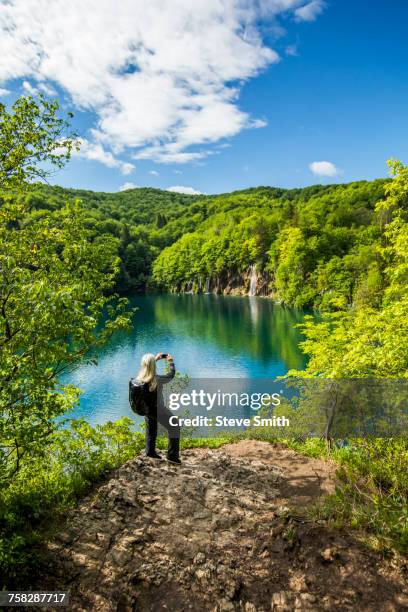 older caucasian woman photographing waterfall with cell phone - bucket list stock pictures, royalty-free photos & images