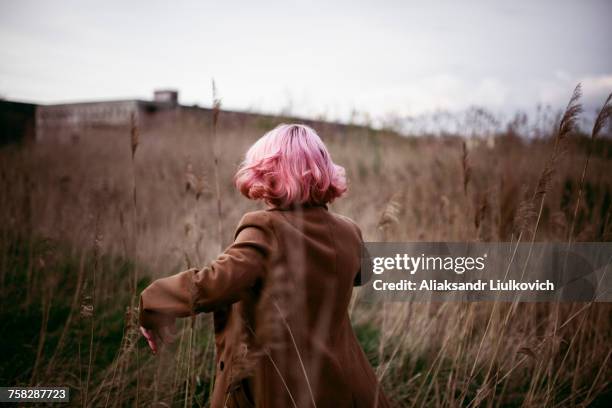 caucasian woman with pink hair running in field - hair colour stock pictures, royalty-free photos & images
