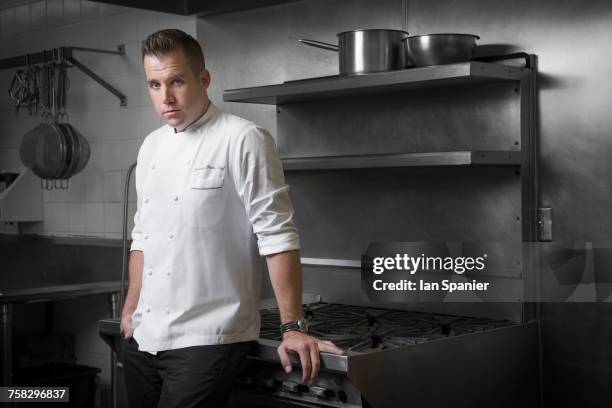 portrait of pastry chef leaning against hob in kitchen - chef portrait stock pictures, royalty-free photos & images