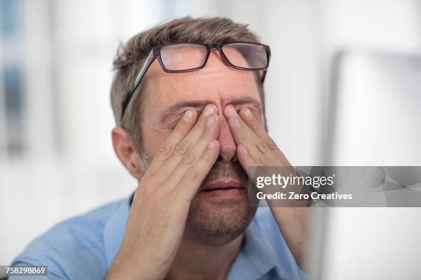 stressed man rubbing eyes - rubbing stock pictures, royalty-free photos & images