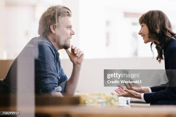 man and woman sitting in cafe, discussing vividly - two executive man coffee shop stock pictures, royalty-free photos & images