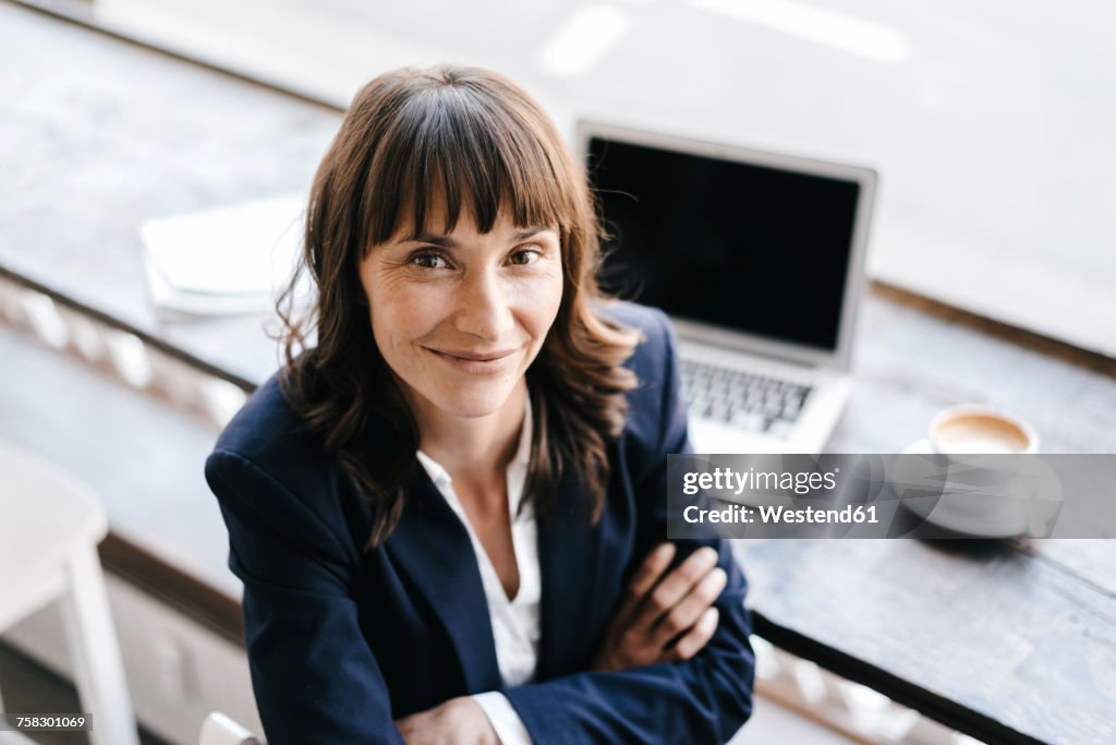 Businesswoman in cafe with arms crossed. looking at camera